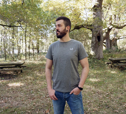 Man standing in a forested area with picnic tables wearing hemp and organic cotton tshirt.
