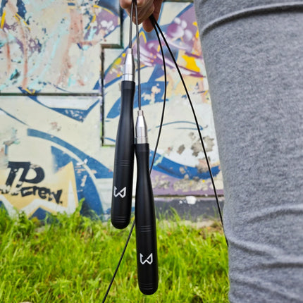 Person holding two black jump ropes with a colorful mural in the background