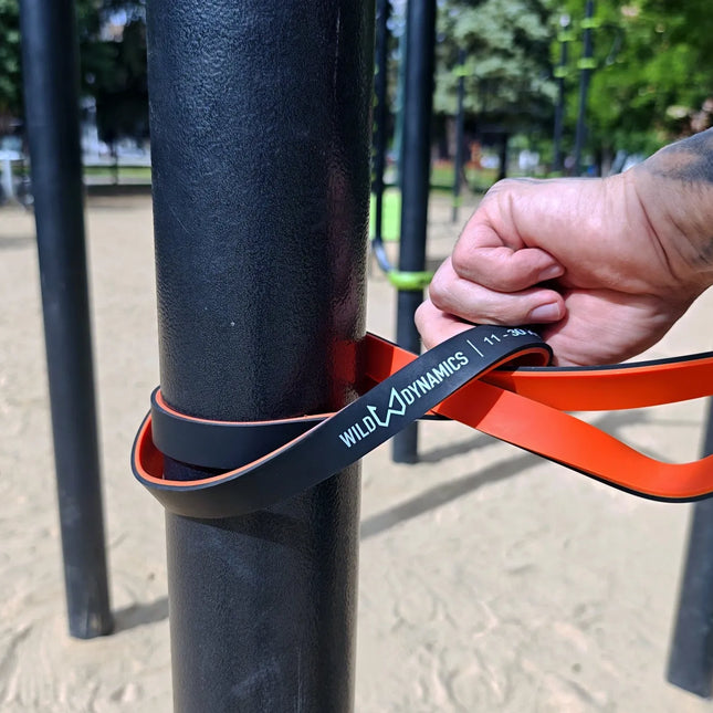 Person using wild dynamics resistance band on outdoor exercise equipment