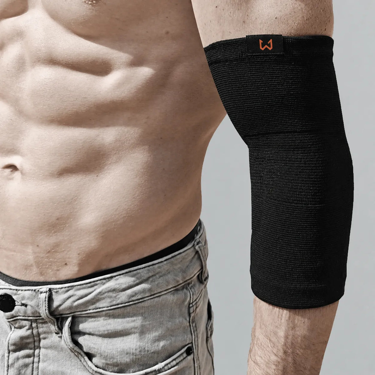 Person wearing a black elbow brace on a plain background