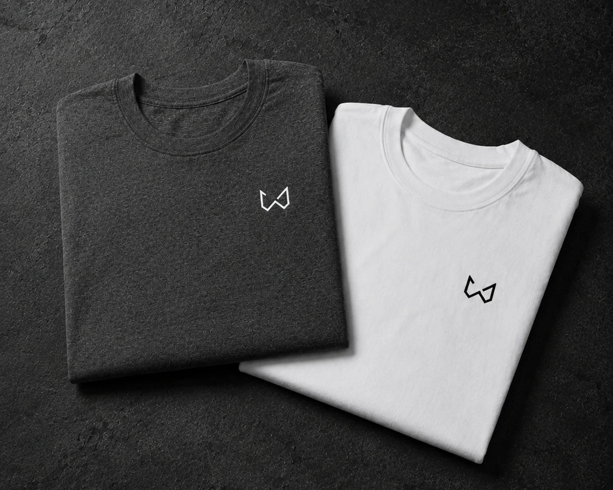 Two folded t-shirts, one gray and one white, with a small logo on a dark surface.
