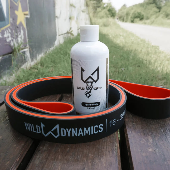 Liquid chalk bottle with 'Wild Dynamics' branding on a wooden surface outdoors.