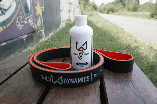 Liquid chalk bottle with 'Wild Dynamics' branding on a wooden surface outdoors.