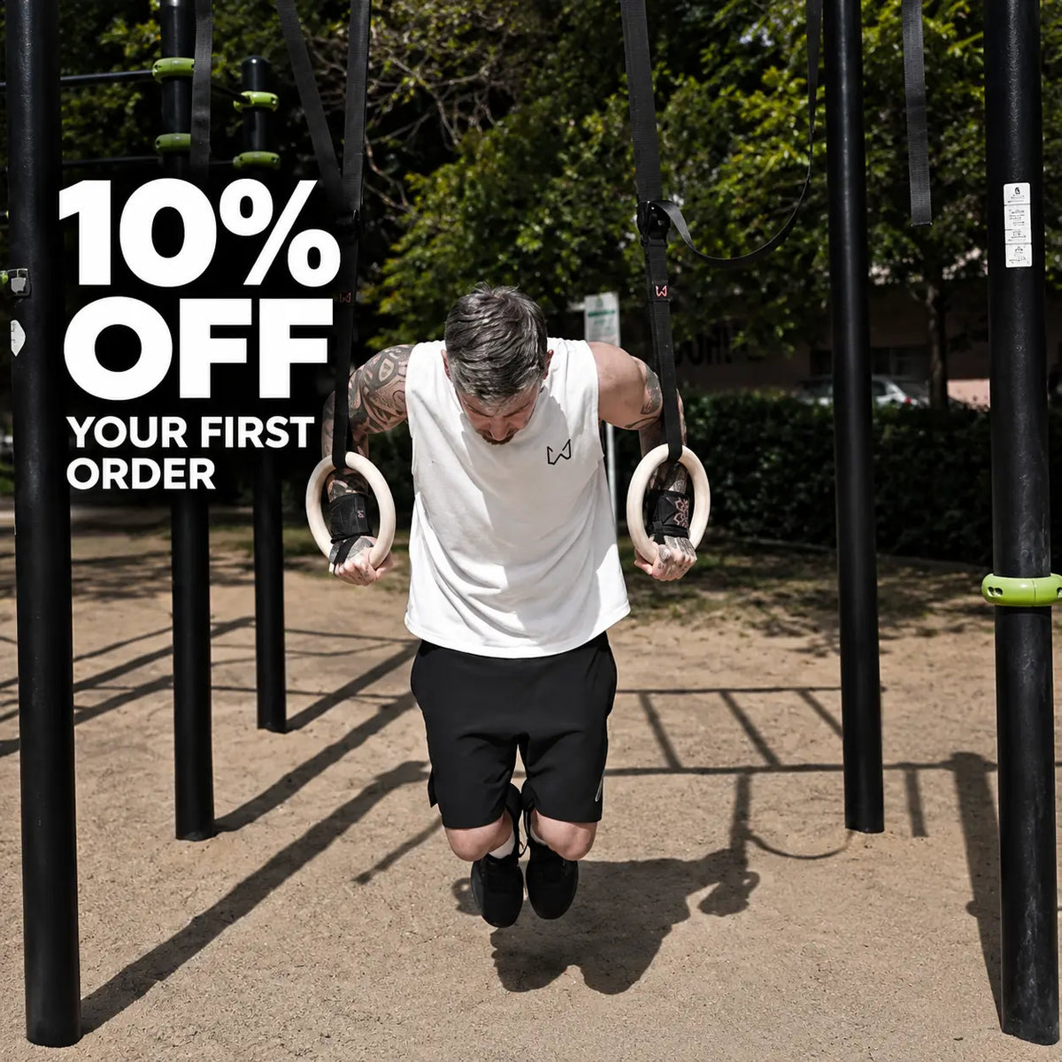 Athlete performing ring dips with wooden gymnastic rings at an outdoor calisthenics park